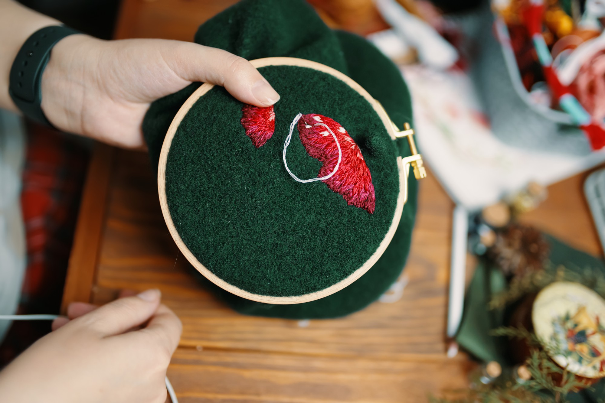 artisan at work stitching floral pattern on hoop